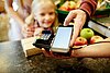 Familie bezahlt in einem Geschäft mittels Smartphone an einem mobilen Kartenlesegerät